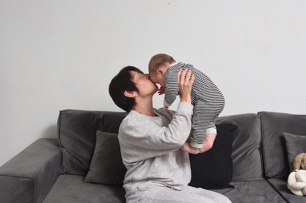 Madre que besa a su bebé en el sofá de casa