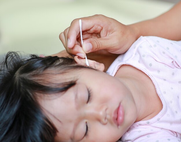 Madre que limpia el oído del bebé con hisopo de algodón.