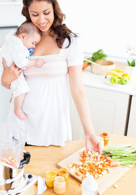 Madre radiante preparando comida para su bebé adorable en la cocina