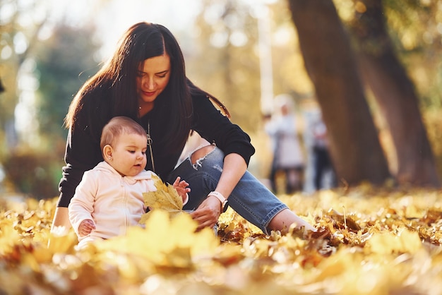 Madre en ropa casual con su hijo está en el hermoso parque de otoño.