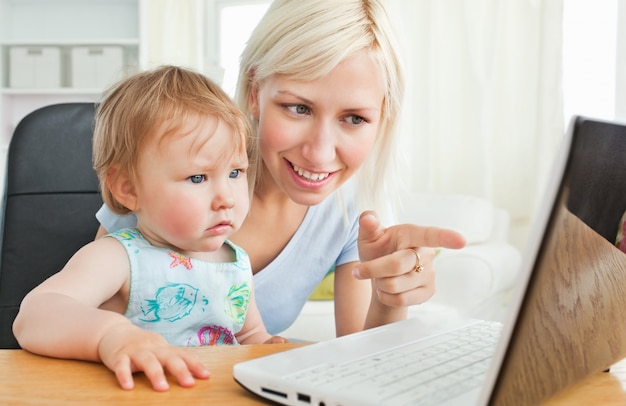 Madre rubia que se divierte con su hija delante de la computadora portátil