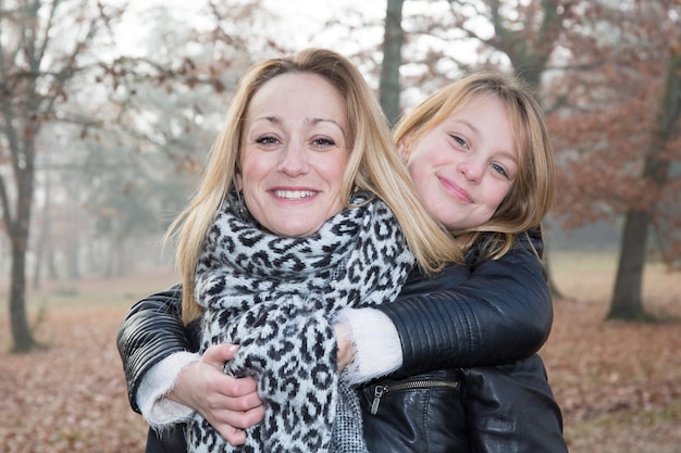 Una madre rubia y su hija en un parque.