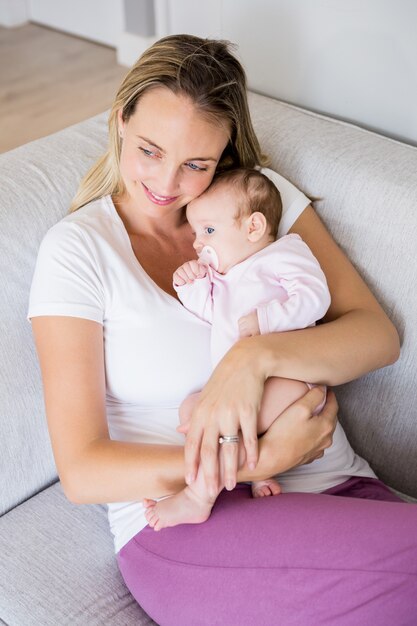 Madre sentada con su bebé en el sofá de la sala de estar