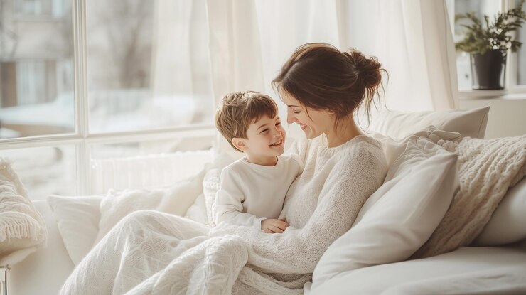 Una madre se sienta en un sofá blanco con su hijo compartiendo un abrazo feliz