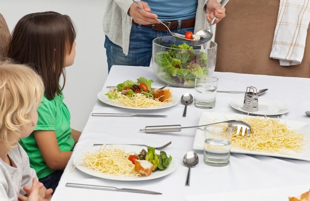 Madre sirviendo ensalada a sus hijos en el almuerzo