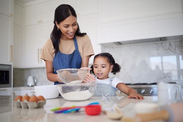 Madre soltera enseñando a su hija habilidades para hornear y uniéndose en la cocina de casa Linda niña aprendiendo a cocinar con su madre sonriente Padre feliz mostrando a un niño curioso cómo tamizar la harina