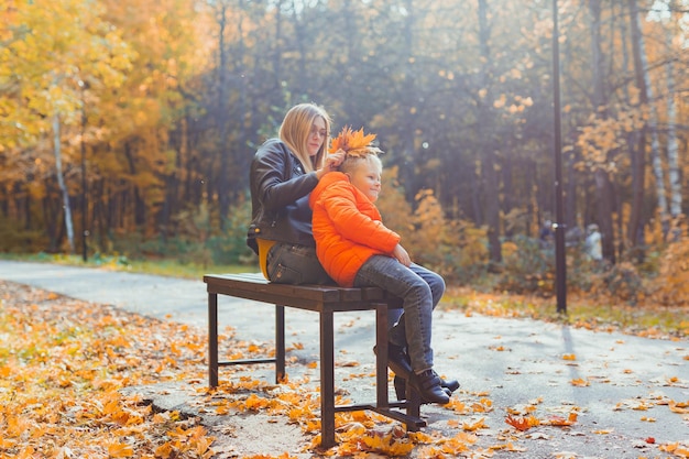 La madre soltera y el niño niño en el otoño en el parque se sientan en la temporada de otoño del banco y el concepto de familia