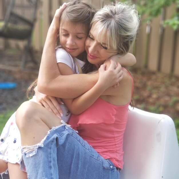 Foto madre sonriente abrazando a su hija al aire libre