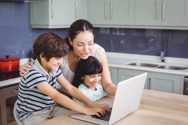 Madre sonriente y niños que trabajan en la computadora portátil