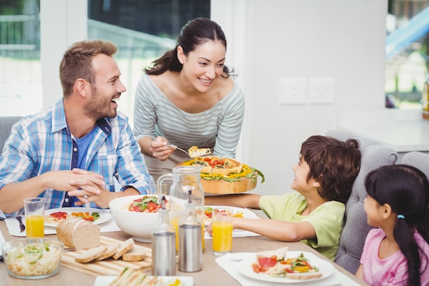 Madre sonriente sirviendo comida a los niños