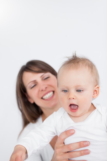 Madre sonriente sosteniendo a su bebé sorprendido