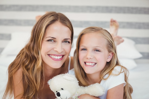 Madre sonriente y su hija en la cama en su casa