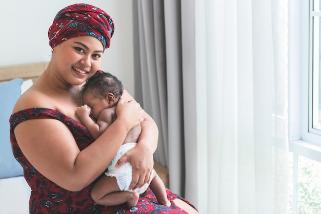 madre sosteniendo a un bebé mitad nigeriano mitad tailandés es un bebé recién nacido de 2 meses durmiendo y feliz