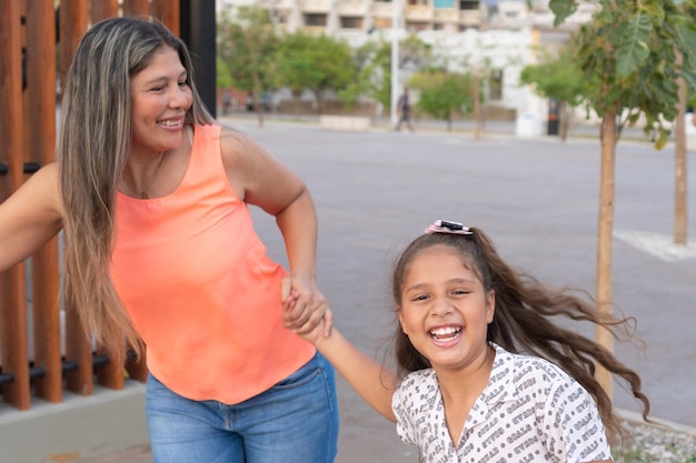 Madre sosteniendo la mano de su hija mientras corre en el parque