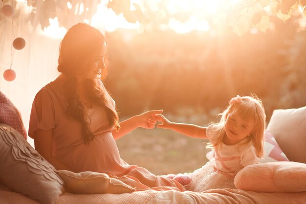 Madre sosteniendo a la niña al aire libre en la luz del sol