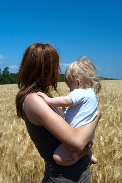 Madre sosteniendo a un niño en el campo de trigo