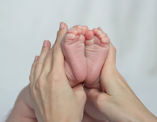 Madre sosteniendo los pies del bebé, hay un concepto o idea de amor, familia y felicidad en el hogar, como madre cuidando al recién nacido