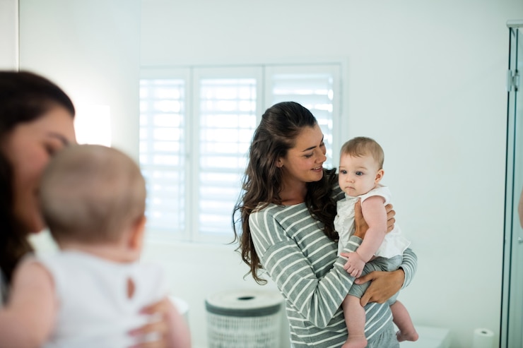 Foto madre sosteniendo a su bebé en el baño en casa