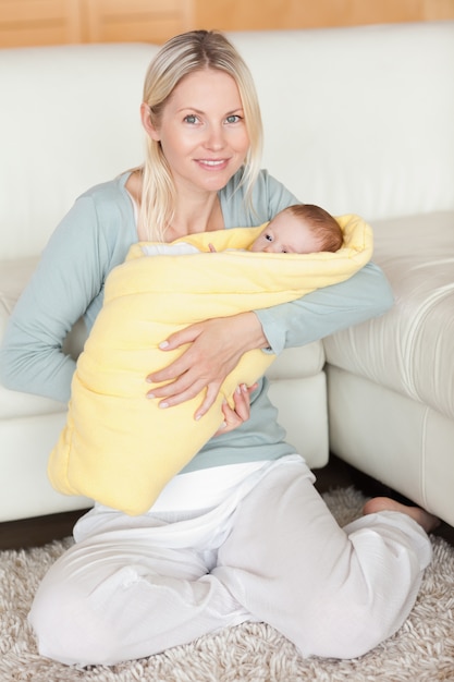 Madre sosteniendo a su bebé que está envuelto en una cubierta