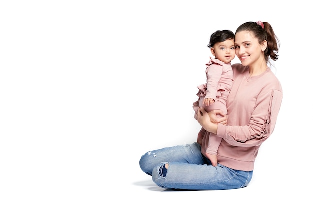 Madre sosteniendo a su hija mientras está sentada en el piso