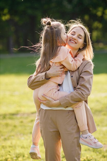 Madre sosteniendo a su hija en sus manos y abrazándose en un parque de primavera