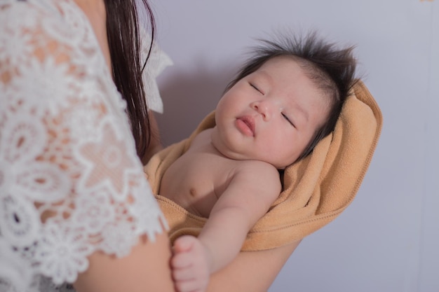 Madre sosteniendo a su lindo bebé recién nacido soñoliento