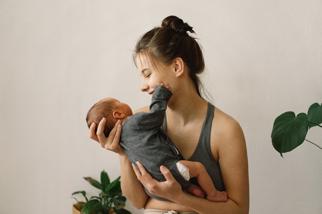 La madre sostiene y abraza a su hijo recién nacido en casa mamá y bebé feliz