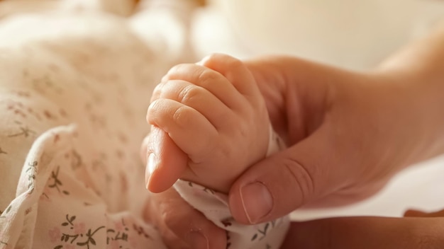Foto la madre sostiene la mano de la hija recién nacida en el dormitorio en casa