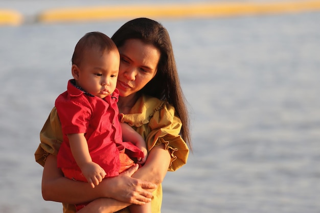 La madre sostiene a su hijo y pasea por la playa