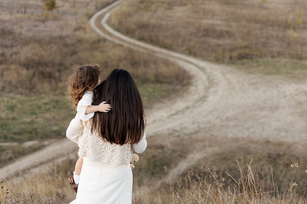 madre sostiene a su pequeña hija linda en sus brazos y la abraza fuertemente