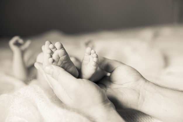 La madre sostiene en sus manos las piernas de su hija recién nacida. foto en estilo retro
