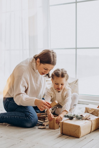 Madre con su hija empacando regalos de Navidad y divirtiéndose