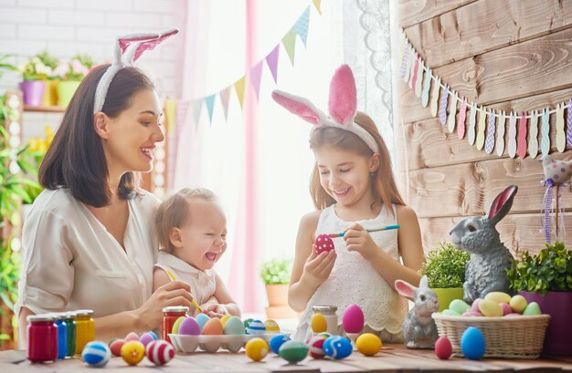 Foto una madre y su hija están pintando huevos la familia feliz se está preparando para pascua