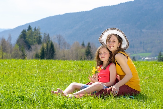 Una madre y su hija con una flor en la boca.