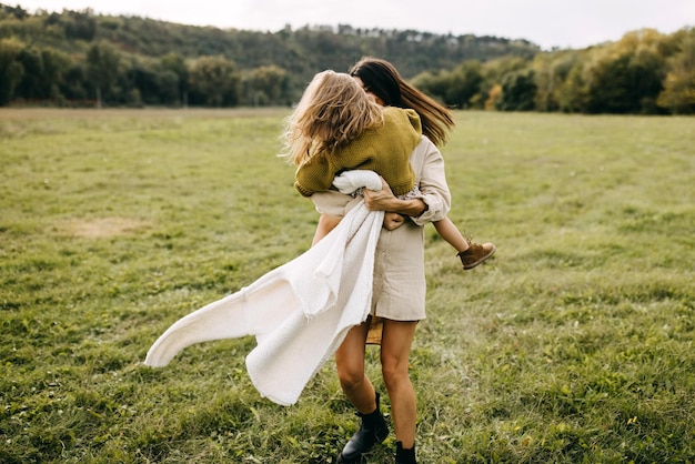 Madre y su hija jugando al aire libre bailando en un campo con hierba verde