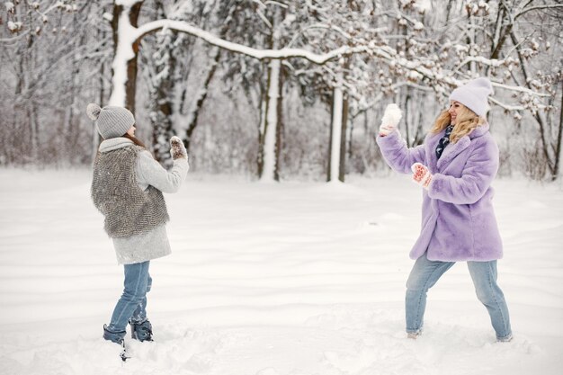 Madre y su hija jugando en bolas de nieve en invierno