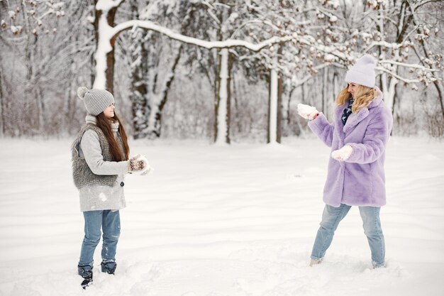 Madre y su hija jugando en bolas de nieve en invierno