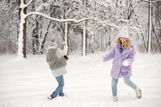 Madre y su hija jugando en bolas de nieve en invierno