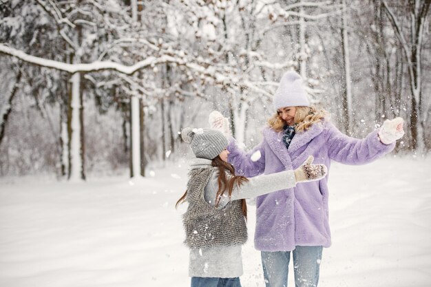 Madre y su hija jugando en bolas de nieve en invierno