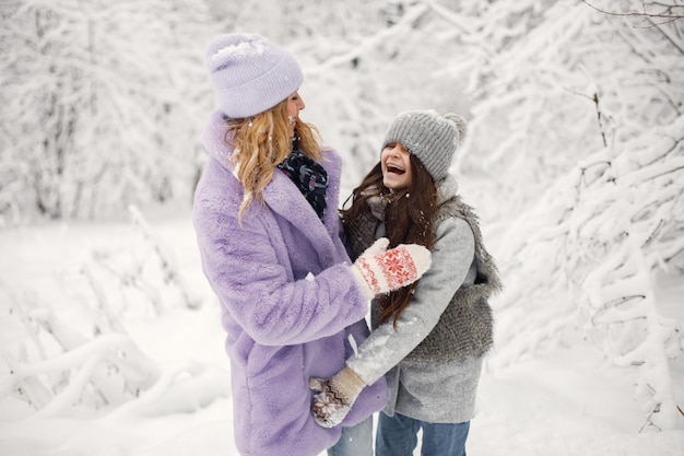 Madre y su hija jugando en bolas de nieve en invierno