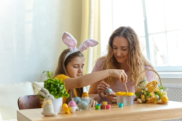 Madre y su hija jugando con huevos pintados.