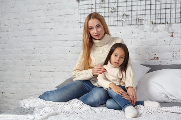 Madre y su hija niña jugando y abrazándose en la cama