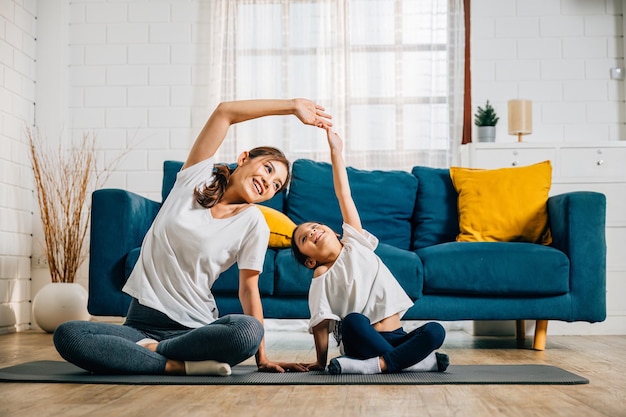 Una madre y su hija pequeña practican yoga juntos centrándose en la relajación y el equilibrio en la acogedora sala de estar