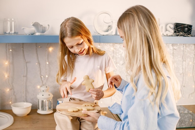 Madre y su hija probando galletas navideñas de jengibre en la cocina