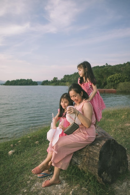 Una madre y su hija se sientan en un tronco junto al lago.