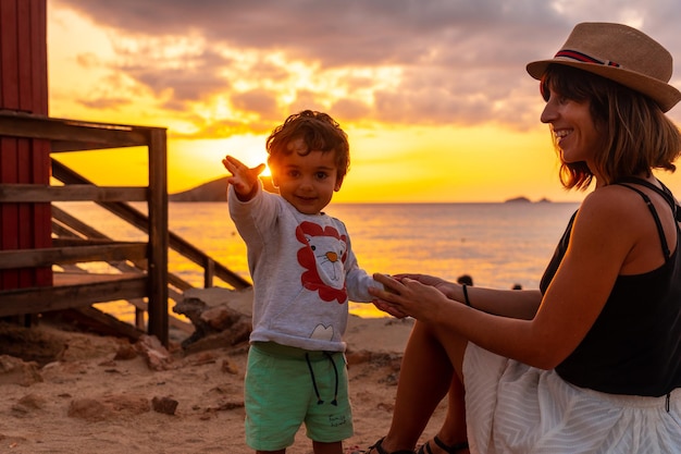 Madre con su hijo al atardecer en la playa de Cala Comte en la isla de Ibiza Balearic