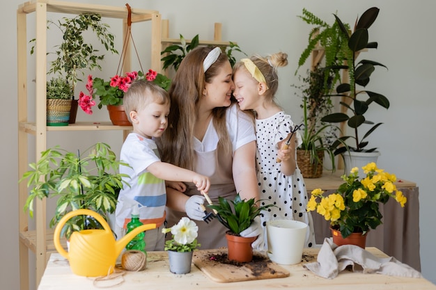 Madre con su hijo e hija en ayunas o trasplante de flores de interior cuidando plantas de interior