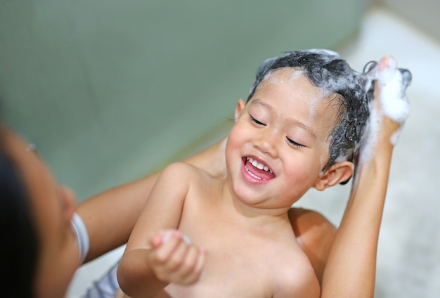 La madre de su hijo la está bañando y lavando con champú.