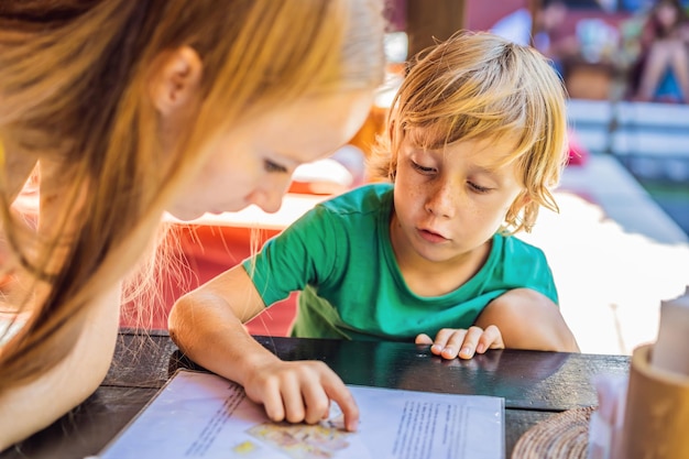 Madre con su hijo mirando el menú en el restaurante