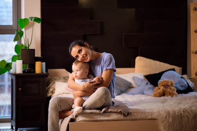 Madre y su hijo niño niña jugando y abrazándose en la cama.